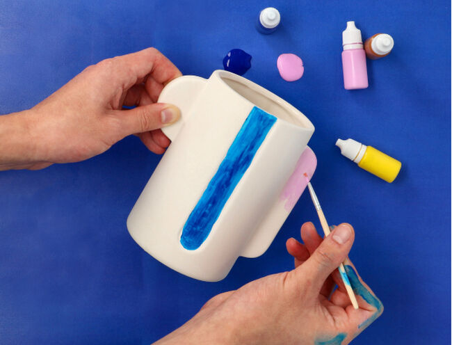 person painting a ceramic mug